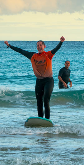 Dziewczynka uczy się surfować i jest podekscytowana możliwością złapania fali