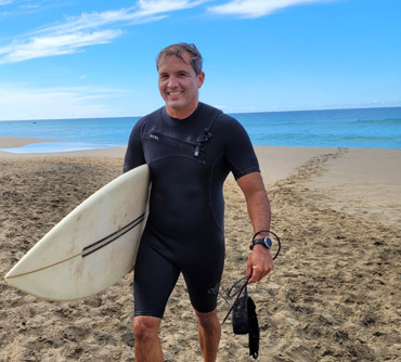 Fede z deską surfingową wyłaniającą się z wody